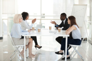 Breach Of Contract Lawyer Washington, DC - Diverse employees sit at table, discussing project in boardroom